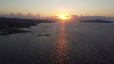 Yunanistan 'ın Girit kentindeki kayalık plajda gün batımının hava manzarası. Gün batımında deniz feneri, sahil boyunca dalgalar....