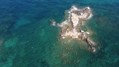 İnsansız hava aracının su altı resiflerindeki görüntüsü ve Akdeniz kıyısındaki şeffaf suyla birlikte plajların yakınındaki kayalıklar. Kamera aşağı bakıyor. Girit, Yunanistan.
