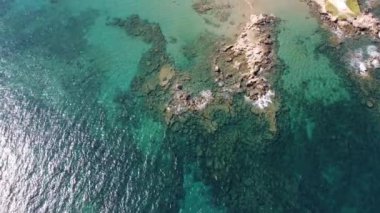 İnsansız hava aracının su altı resiflerindeki görüntüsü ve Akdeniz kıyısındaki şeffaf suyla birlikte plajların yakınındaki kayalıklar. Kamera aşağı bakıyor. Girit, Yunanistan.