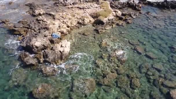 Flygvideo vy från drönare på undervattensrev och kustklippor i Medelhavet nära stränder med klart transparent vatten. Kameran tittar ner. Kreta, Grekland. — Stockvideo