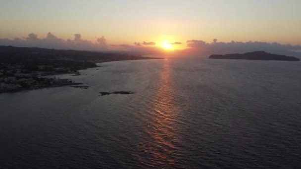 Luftaufnahme des Sonnenuntergangs am felsigen Strand mit Leuchtturm auf Kreta, Griechenland. Leuchtturm im Sonnenuntergang mit Wellen entlang der Uferpromenade. — Stockvideo