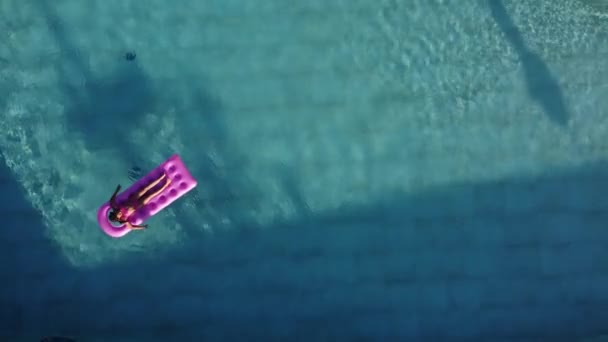 Das Mädchen entspannt sich auf einer aufblasbaren Matratze im Pool und nimmt Luftbäder. — Stockvideo
