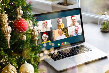 Noel selamları çevrimiçi. Beyaz kazaklı ve kırmızı şapkalı bir kadın arkadaşlarına, ailelerine ve online alışveriş için bilgisayar kullanıyor.