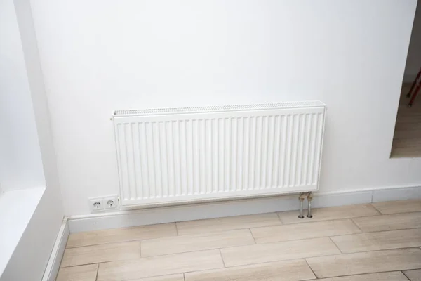 Riscaldamento radiatore in una stanza bianca con pavimento in legno laminato — Foto Stock