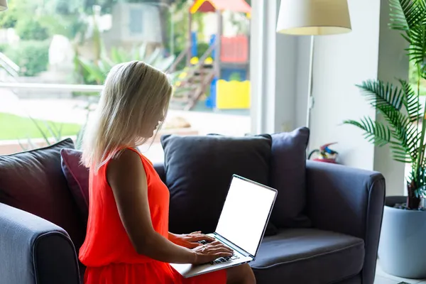 Jonge vrouw zit te werken op laptop in openbare wifi gebied, typen, mensen passeren op de achtergrond — Stockfoto