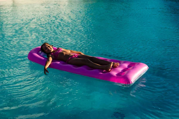 Petite fille flotte sur un matelas gonflable dans la piscine — Photo