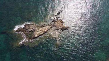 İnsansız hava aracının su altı resiflerindeki görüntüsü ve Akdeniz kıyısındaki şeffaf suyla birlikte plajların yakınındaki kayalıklar. Kamera aşağı bakıyor. Girit, Yunanistan.