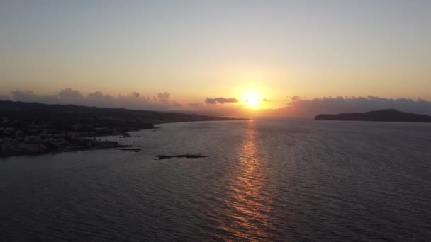 希腊克里特岛的岩石海滩上的落日空中景观，还有灯塔。夕阳西下的灯塔，波涛汹涌，沿着木板路. — 图库视频影像