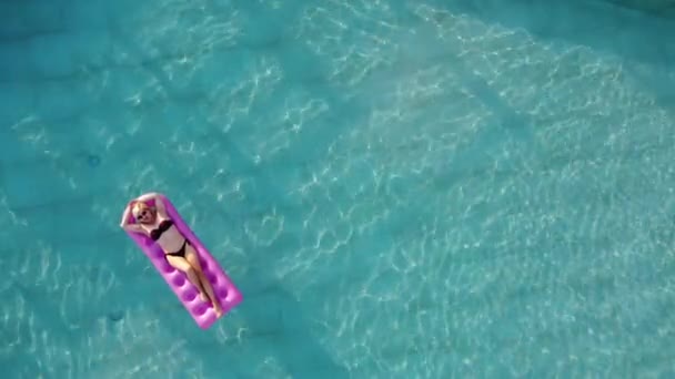 Молода красива жінка на повітряному матраці в басейні — стокове відео