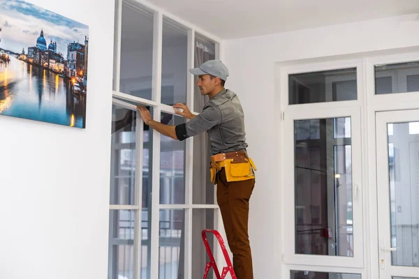 Bauarbeiter montiert Metallprofil für Trennwand im Inneren, während er ein neues Haus baut oder Renovierungsarbeiten durchführt, von seinem Rücken aus gesehen. — Stockfoto