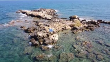 İnsansız hava aracının su altı resiflerindeki görüntüsü ve Akdeniz kıyısındaki şeffaf suyla birlikte plajların yakınındaki kayalıklar. Kamera aşağı bakıyor. Girit, Yunanistan.