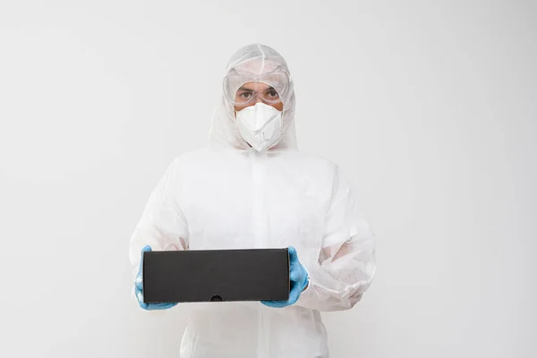 Beyaz arka planda elinde bir paketle tehlikeli madde giysisi içinde duran bir adam. — Stok fotoğraf