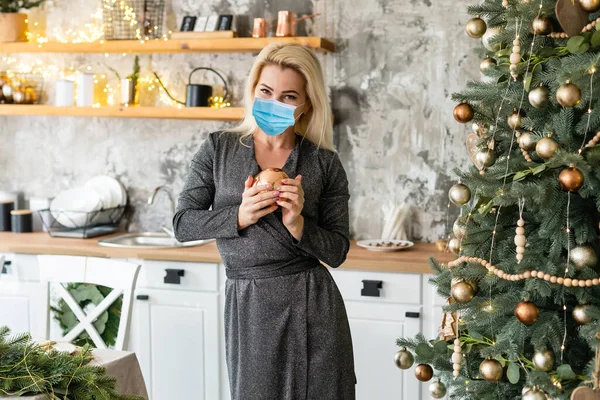 Tıbbi maskeli kadın, arka planda Noel ağacı bokeh — Stok fotoğraf