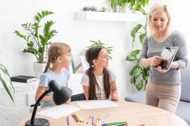 İnternette internet öğrenen iki küçük kız çocuğu annelerinin yardımıyla bilgisayar kullanarak, öğreterek ve teşvik ederek ev ödevi yapıyor. Kız ve kız kardeş evde birlikte eğitim almaktan mutlular.