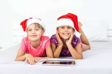 Noel, Noel, Noel, kış, mutluluk konsepti - tabletle oynayan iki sevimli kıvırcık kız