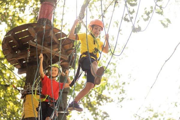 Lindos niños. Niño y niña escalando en una estructura de patio de cuerda en el parque de aventuras — Foto de Stock