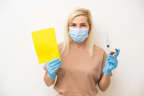 Tıbbi maskeli bir kadın, aşılama sertifikası taşıyor. Yetişkinler, kovid 19 korona virüsüne karşı aşısı hakkındaki bilgileri gösteriyor.. — Stok fotoğraf