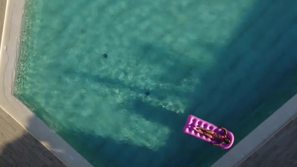 Kleines Mädchen schwimmt auf aufblasbarer Matratze im Pool — Stockvideo