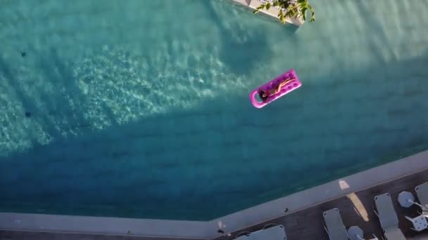 Das Mädchen entspannt sich auf einer aufblasbaren Matratze im Pool und nimmt Luftbäder. — Stockvideo