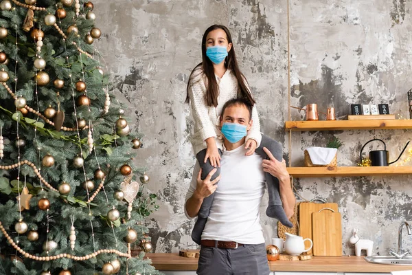 Mutlu bir aile, Noel ağacının yakınındaki COVID-19 koronavirüsünden dolayı tıbbi maske takar. Xmas tatili — Stok fotoğraf