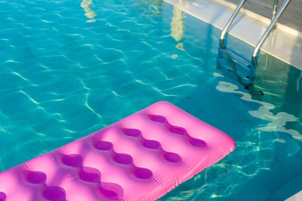 Розовый матрас в бассейне солнечный день — стоковое фото