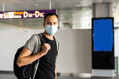 Coronavirus zatürree salgını sırasında havaalanında tek kullanımlık tıbbi maske takan adam. Salgın sırasında tedbirlerin korunması ve önlenmesi.
