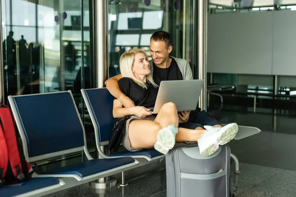 Pareja encantadora con ordenador portátil en el aeropuerto — Foto de Stock