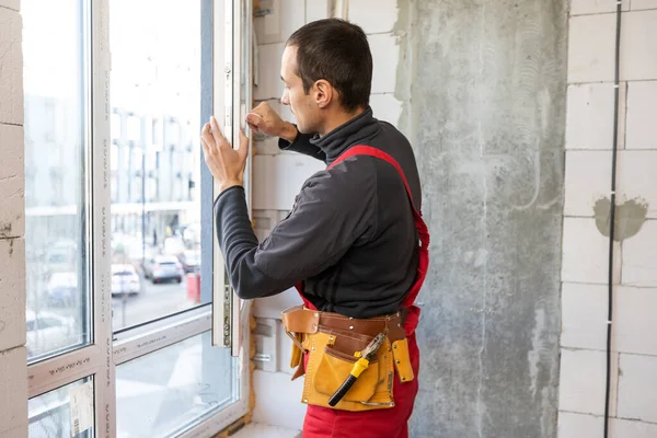 Byggnadsentreprenör reparerar fönster i huset. — Stockfoto