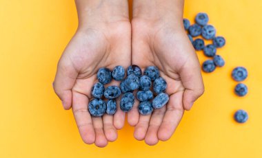 Bir avuç dolusu yaban mersini ve açık sarı arka planda mesajlaşmak için yeri olan çocuklar.