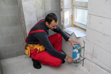 İşçi ısıtma bataryasını tamir ediyor.
