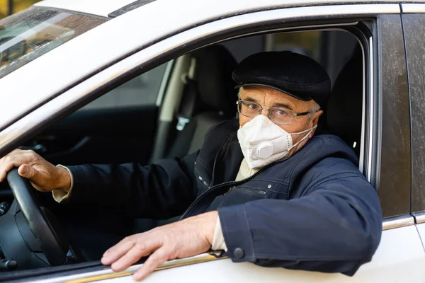 Літній чоловік у масці для обличчя входить до своєї машини вдома . — стокове фото
