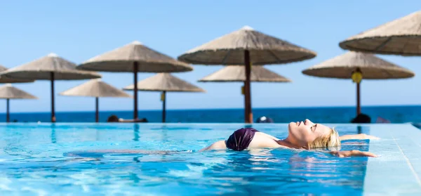 Egy fiatal nő, aki a nyári szünetben a medencében pihen. Szőke, fehér. — Stock Fotó