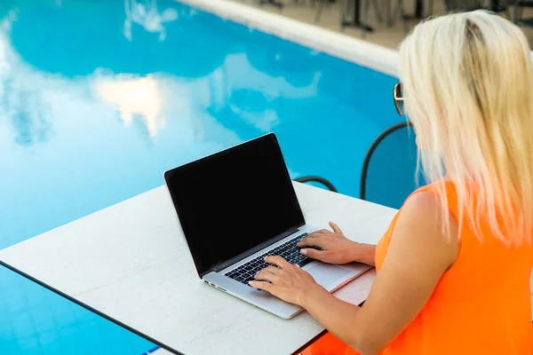Sexy vrouw zonnebaden en werken op een chaise lounge in de buurt van zwembad buiten — Stockfoto
