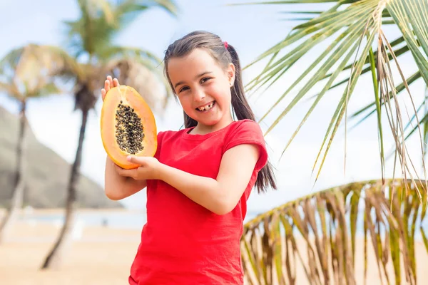 Маленька дівчинка тримає папаю на пляжі — стокове фото