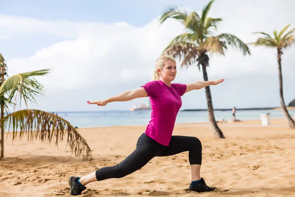 Stile di vita estivo ritratto di abbastanza felice ragazza con abbronzato corpo sexy. Fare yoga, sorridere e sedersi vicino all'albero sulla spiaggia dell'isola tropicale con acqua limpida. — Foto Stock