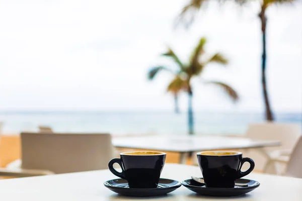 Stäng upp kaffekoppen på bord av trä på solnedgången eller sunrise beach — Stockfoto