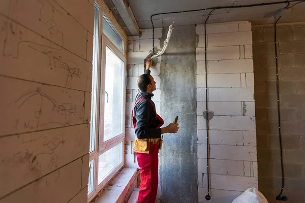 ハンサムな若い電気技師が住宅建設現場のスイッチボードに取り組んでいます — ストック写真