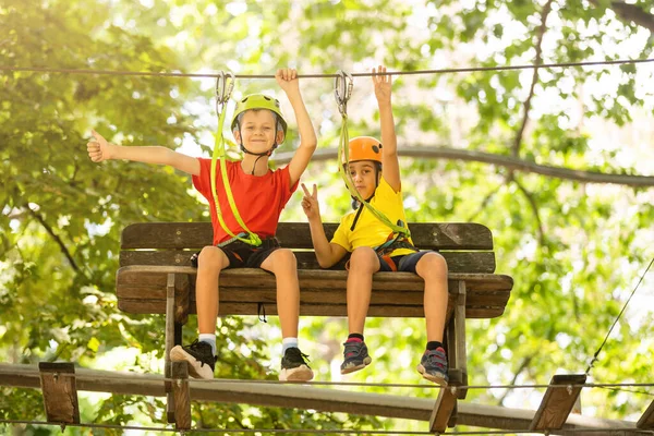 Child in forest adventure park. Kids climb on high rope trail. Agility and climbing outdoor amusement center for children. Little girl playing outdoors. School yard playground with rope way. — Stock Photo, Image
