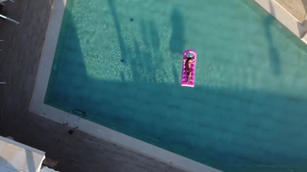 Το κορίτσι χαλαρώνει σε ένα φουσκωτό στρώμα στην πισίνα, κάνοντας αφρόλουτρα. — Αρχείο Βίντεο