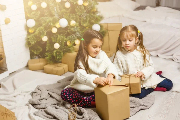 Due ragazze davanti all'albero di Natale con regali e caminetto — Foto Stock
