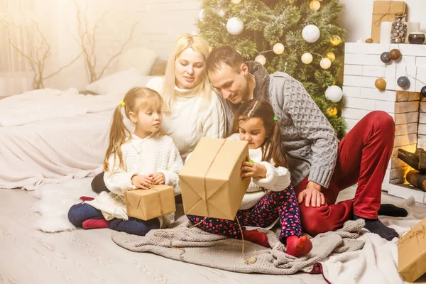 クリスマスツリーの前で贈り物を交換する家族 — ストック写真
