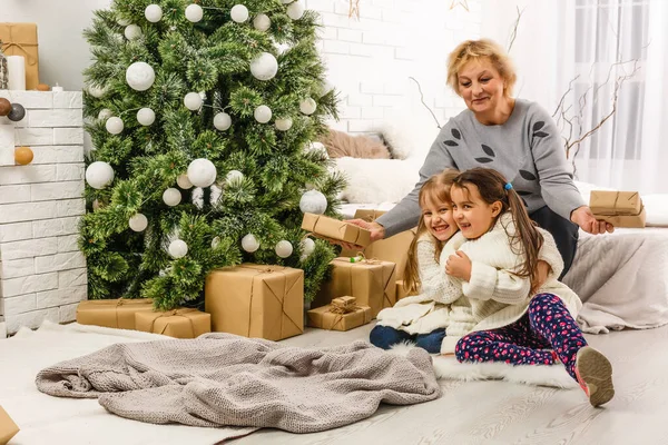 Duas meninas na frente da árvore de natal com presentes e fogo lugar — Fotografia de Stock