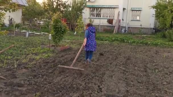 Little girl on a sunny day in the garden with a hoe — Stock Video