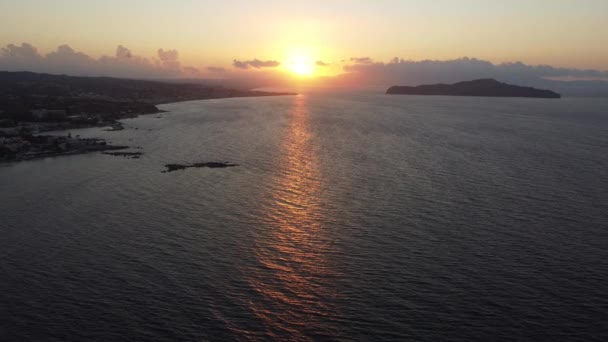 Flygfoto över solnedgången på stenig strand med fyr på Kreta, Grekland. Fyrtorn i solnedgången med vågor längs strandpromenaden. — Stockvideo
