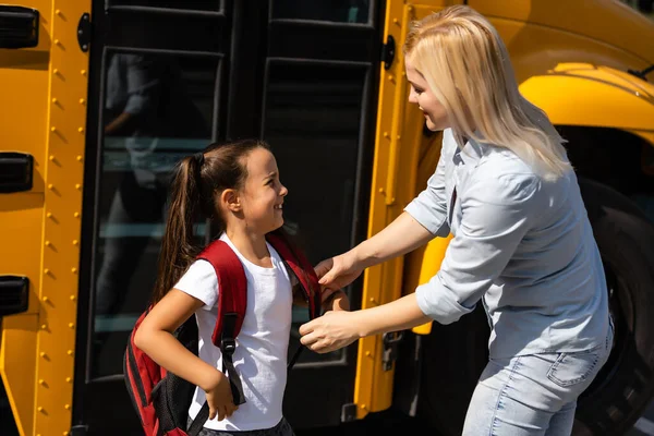 Anne kızını okul otobüsünün yanına getiriyor. Okula geri dön.