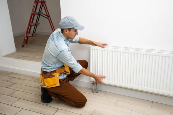 Мужчина меняет отопление в доме, радиаторы. Концепция современного отопления, замена старого на новый. Тепло в доме — стоковое фото