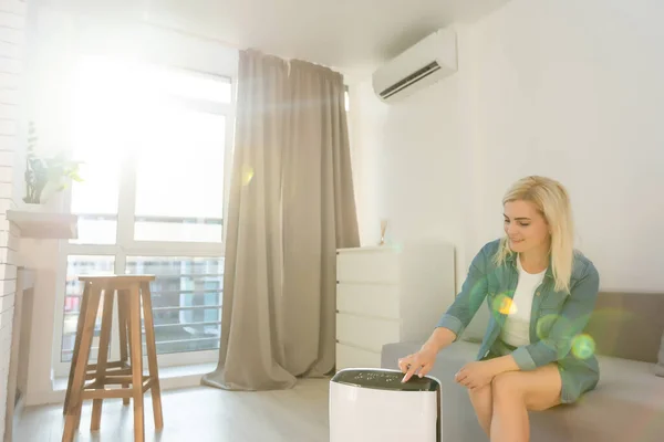 Atraktivní žena s čističem vzduchu v moderním domě. — Stock fotografie