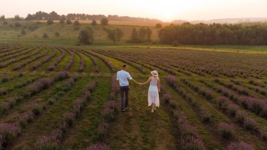 Mor lavanta tarlasında güzel, mutlu bir çift. Çiçekli arazide eğleniyorlar. Yaz doğası, aşk konsepti.