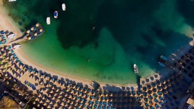 Arnavutluk 'un güzel Ksamil plajında güneşlik şemsiyeler ve şezlonglar.