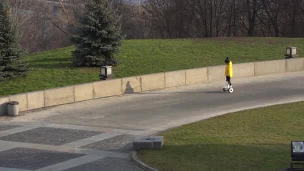 Uma menina montando uma scooter elétrica. Transporte ecológico pessoal, scooter giroscópio, roda de balanço inteligente. Transporte elétrico popular — Vídeo de Stock